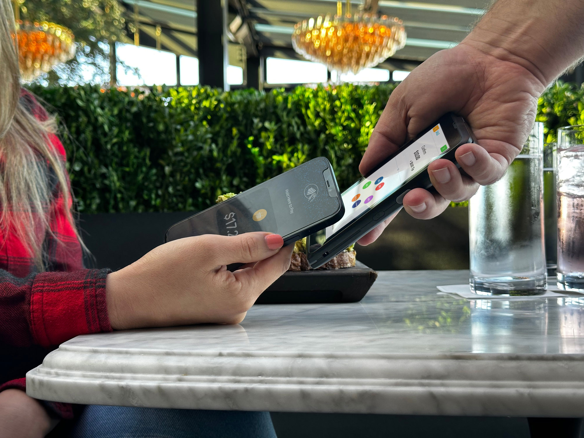 Woman holding a phone near a no fee credit card processing payment terminal in the hand of a waiter